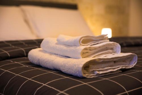 een stapel handdoeken bovenop een bed bij Doraci Home in Conversano