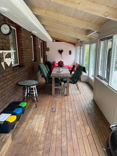 een afgeschermde veranda met een tafel en stoelen bij Spacious house with sauna 2 bathrooms and indoor pingis table! in Hestra