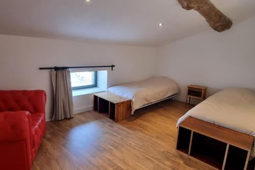 1 Schlafzimmer mit 2 Betten und einem roten Sofa in der Unterkunft Métairie du Château in Aussillon