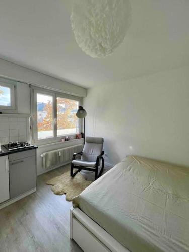 a bedroom with a bed and a chair and a kitchen at Gemütliche 1,5 Wohn.: Komfort und Still in Bern