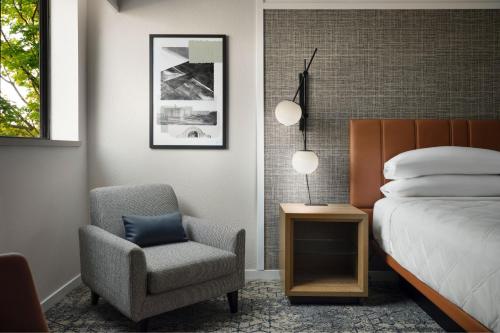a bedroom with a bed and a chair and a bed and a lamp at Sheraton Grand Rapids Airport Hotel in Grand Rapids