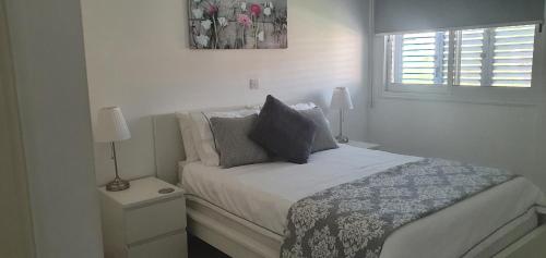 a bedroom with a bed with two night stands and a window at Sea view Apartment Peyia, Paphos in Paphos City