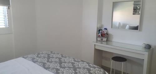 a white bedroom with a bed and a mirror at Sea view Apartment Peyia, Paphos in Paphos City