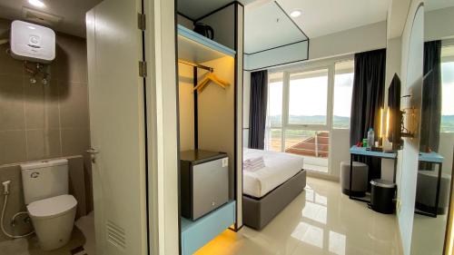 a small bathroom with a toilet and a bedroom at REOTEL at Kaina Tower - The Nove in Telukmataikan