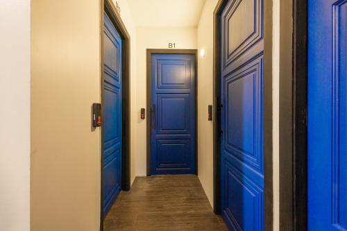 a hallway with two blue doors and a wooden floor at Marco Polo Phuket Poshtel & Bistro in Phuket