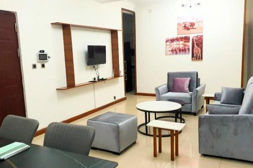 a waiting room with chairs and a tv and a table at Les Alizés Appartement meublé 3 in Toamasina