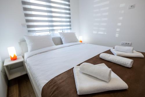 a bedroom with a large white bed with two towels on it at M&A Apartmani in Vrdnik