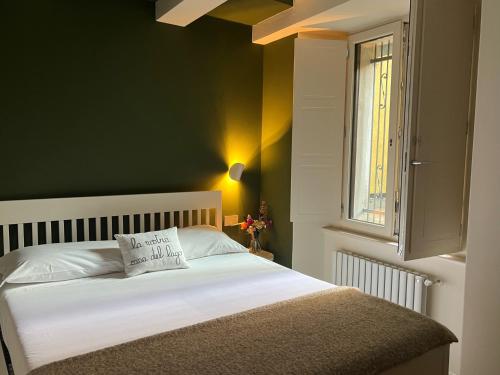a bedroom with a white bed with a green wall at LaLucia Luxury Suite Lake Como in Argegno