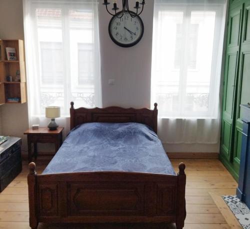 a bedroom with a bed and a clock on the wall at Maison de la Lys in Aire-sur-la-Lys