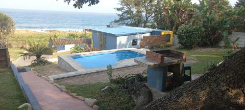 a small swimming pool in front of a house with the ocean at Blue Space Beach house in Port Shepstone