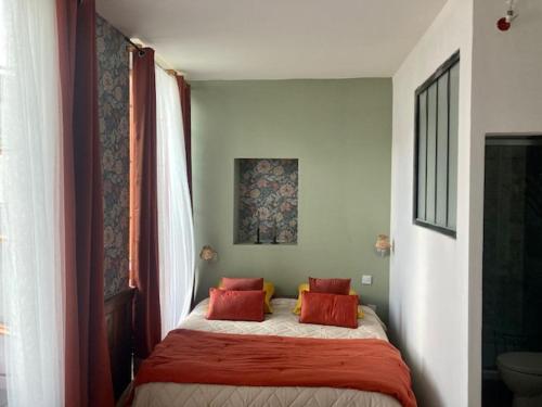una camera da letto con un letto con cuscini rossi di Une maison de famille a Oloron-Sainte-Marie