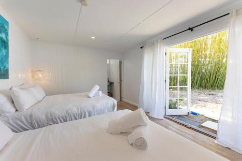 two beds in a white room with a window at Nala Cottage at Patonga in Patonga Beach