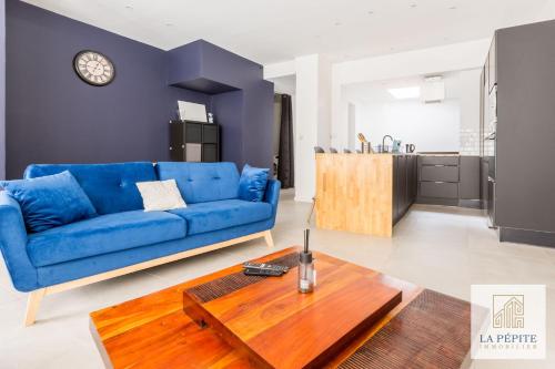 een woonkamer met een blauwe bank en een tafel bij Atelier 46 - Appartement 2 chambres. in Valenciennes