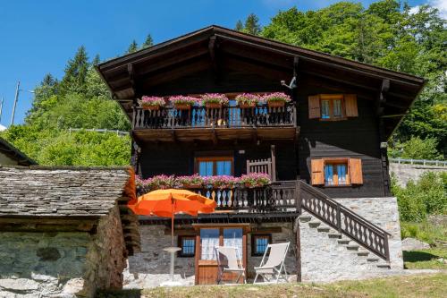 une maison avec un parasol orange devant elle dans l'établissement Incanto Walser Apartments Testa, à Macugnaga