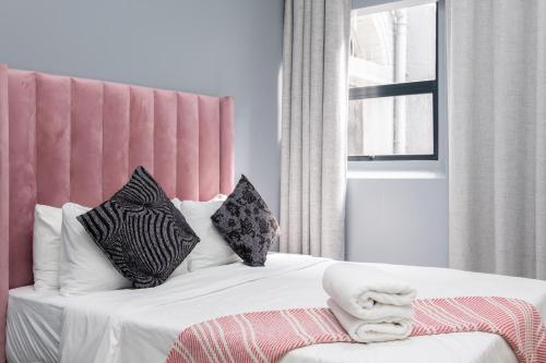 1 dormitorio con 1 cama con cabecero rosa y almohadas en Cape palm royal guest house, en Ciudad del Cabo