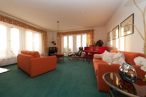 a living room with orange furniture and a red piano at Villa Meerblick Warnemünde - Ferienwohnung mit Meerblick in erster Reihe zum Strand und Promenade in Warnemünde