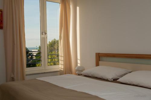 1 dormitorio con cama y ventana grande en Villa Meerblick Warnemünde - Ferienwohnung mit Meerblick in erster Reihe zum Strand und Promenade en Warnemünde