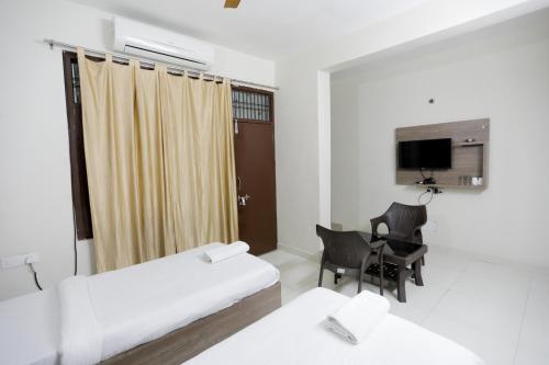 a hotel room with two beds and a desk and a television at Kashi Stay in Varanasi