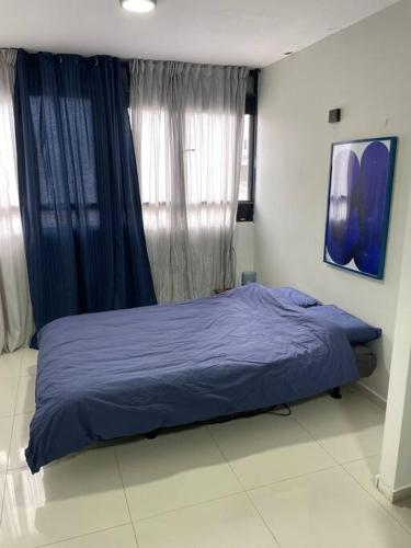 a bed in a bedroom with blue sheets and curtains at Dream Studio in Herzliya