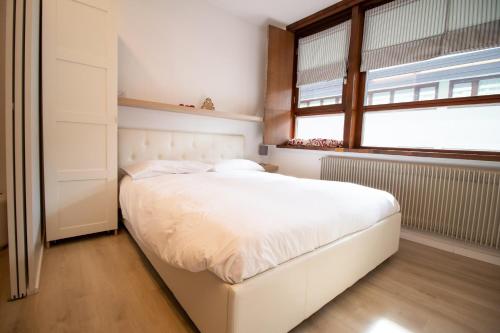 a white bed in a bedroom with a window at Casa Franz in Val di Fassa by Zoom In Earth in Mazzin