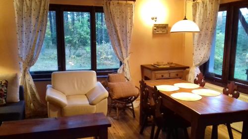 comedor con mesa, sillas y ventanas en EKOLANDIA domek w lesie na wyłączność, en Tuszkowy