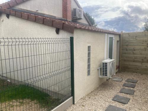 einen Zaun vor einem Haus mit Klimaanlage in der Unterkunft Maisonnette neuve avec jardin privatif in Saran