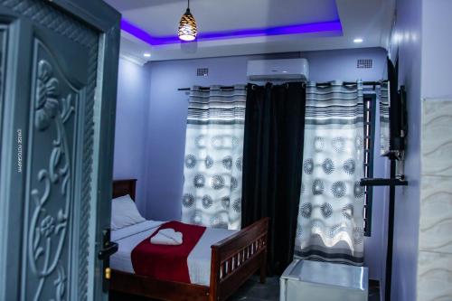 Stay Simple Lodge في لوساكا: غرفة نوم صغيرة مع سرير وستائر