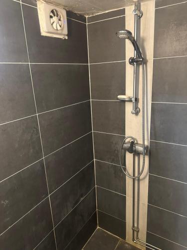 a shower in a bathroom with black tiles at Room B in Malmö
