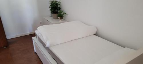 リスボンにあるCozy Room near Metro & Airportの鉢植えの植物2本が備わる部屋の白いベッド1台