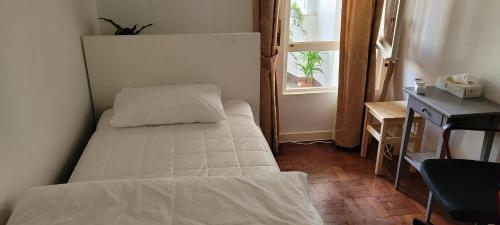 een kleine slaapkamer met een bed en een raam bij Cozy Room near Metro & Airport in Lissabon