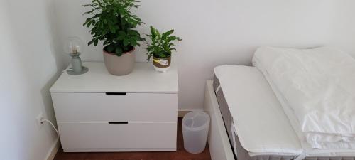 een wit nachtkastje met twee planten naast een bed bij Cozy Room near Metro & Airport in Lissabon