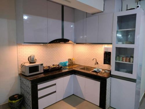 una cucina con armadietti bianchi e forno a microonde di Dorjay House. a Darjeeling
