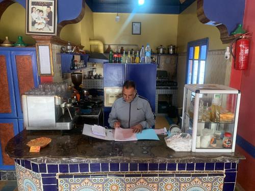 un homme assis à un comptoir dans une cuisine dans l'établissement AMRAOUI Apartment, à Moulay Ali Chérif