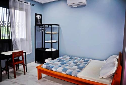 um quarto com uma cama, uma mesa e uma cadeira em Résidence Sampo em Ouagadougou