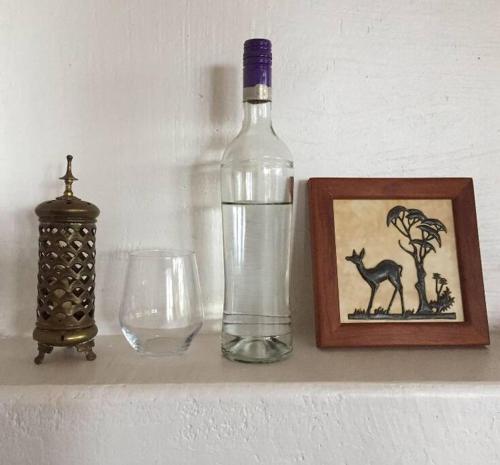 een fles water naast een foto en een glas bij Gongali House - Karatu Rewilded in Karatu