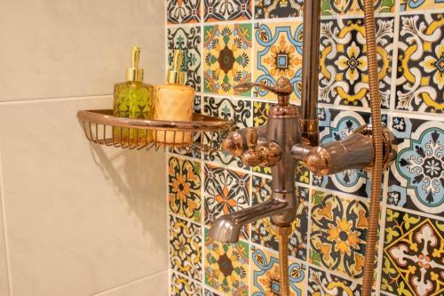 a bathroom with a faucet and a tile wall at Siri Ratchadamnoen Bangkok Hotel in Bangkok