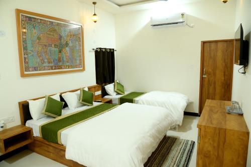 um quarto com duas camas e um quadro na parede em The Travel Bug Jaisalmer em Jaisalmer
