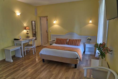 een slaapkamer met een bed, een tafel en een bureau bij Auberge les Oliviers in Lucciana