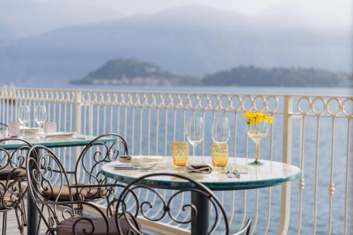un tavolo con sedie e bicchieri da vino su un balcone di La Darsena Boutique Hotel & Restaurant a Tremezzo