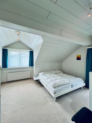 ein weißes Schlafzimmer mit einem Bett im Dachgeschoss in der Unterkunft Casa Lilly - CharmingStay in Flumserberg