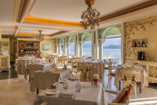 un restaurante con mesas y sillas blancas y ventanas en La Darsena Boutique Hotel & Restaurant en Tremezzo