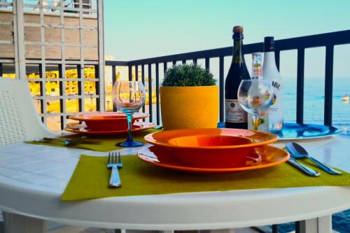 a table with plates and wine glasses on a balcony at Unobstructred seaviews, 2BR, Kingbeds, Fully ACd in Marsaskala