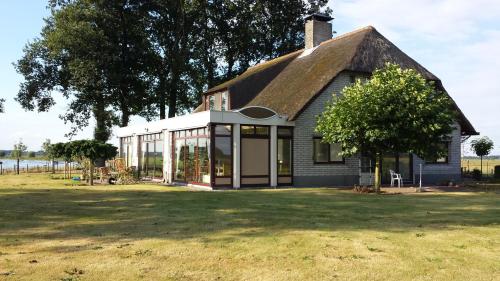 a small house with a thatched roof on a field at B&B Krachtwijk in Soest