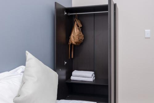 a closet with towels and a bag and a bed at Cape palm royal guest house in Cape Town