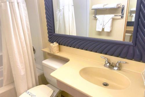 a bathroom with a sink and a mirror and a toilet at Ramada by Wyndham Los Angeles/Wilshire Center in Los Angeles