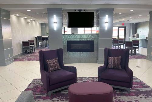 a lobby with two chairs and a flat screen tv at La Quinta Inn & Suites by Wyndham Tulsa Midtown in Tulsa