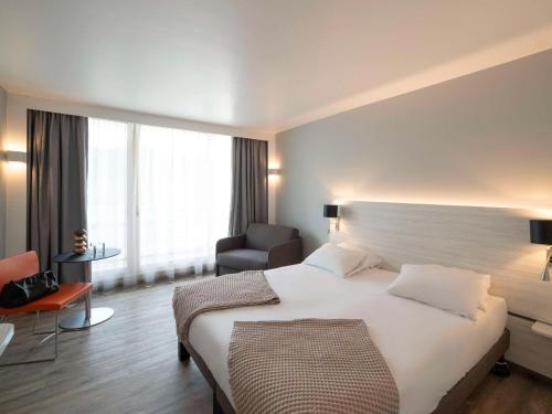 ein Hotelzimmer mit einem großen Bett und einem Stuhl in der Unterkunft Novotel La Grande Motte Golf in La Grande-Motte