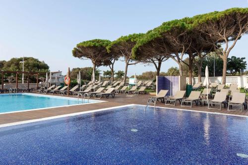 a swimming pool with chaise lounges and chairs at Alua Illa de Menorca in S'Algar