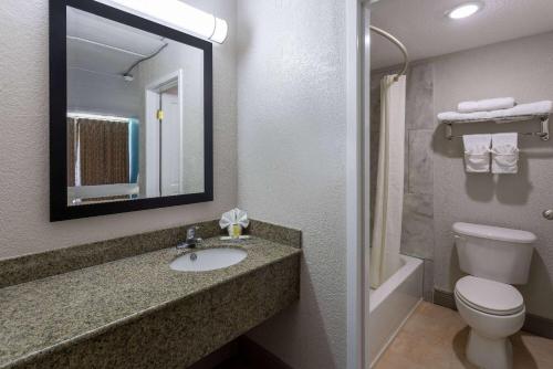 ein Badezimmer mit einem Waschbecken, einem WC und einem Spiegel in der Unterkunft Travelodge by Wyndham Kingsland GA in Kingsland