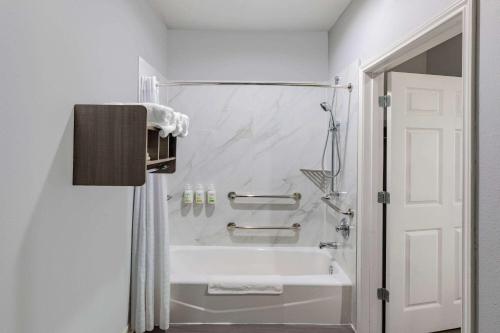 a white bathroom with a tub and a sink at Baymont by Wyndham Freeport Texas in Freeport